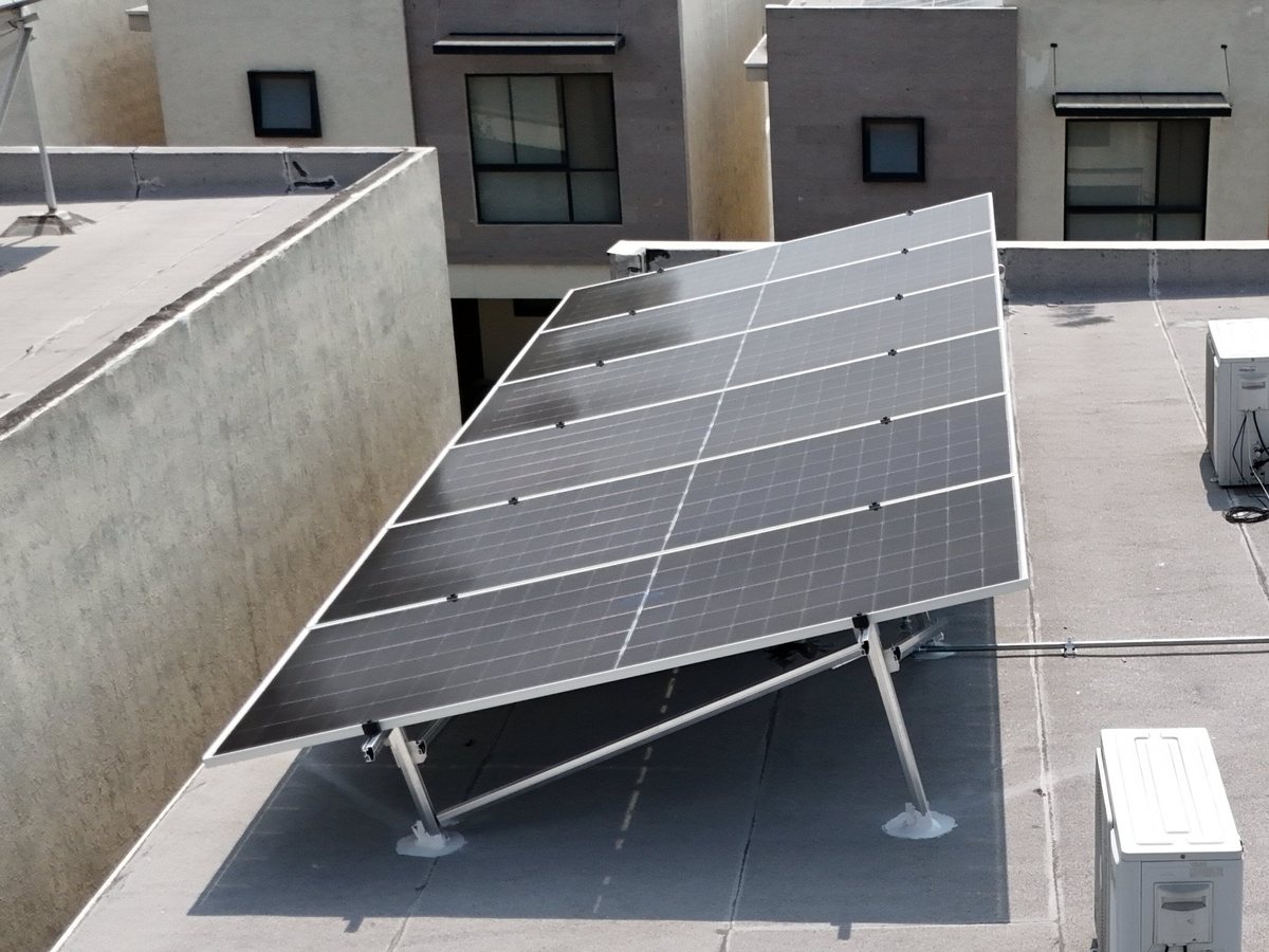 Vista desde dron de seis paneles solares inclinados sobre la losa de una casa en un fraccionamiento