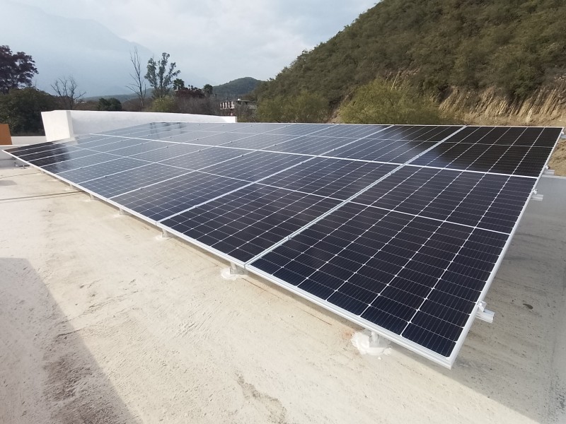 Paneles solares sobre losa plana, con un cerro con vegetación detrás