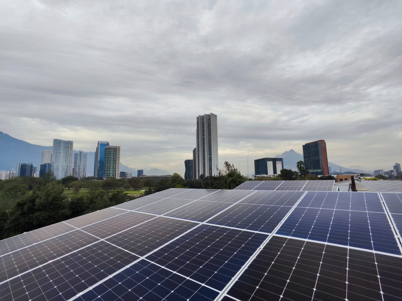 Paneles solares sobre una azotea, con las torres de Monterrey y la sierra al fondo